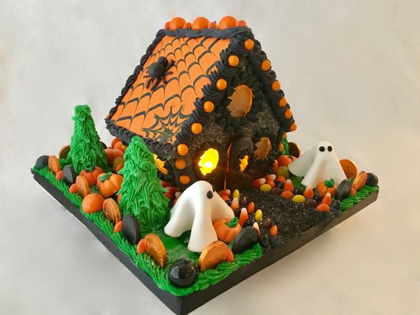 small orange and black gingerbread house with ghosts.