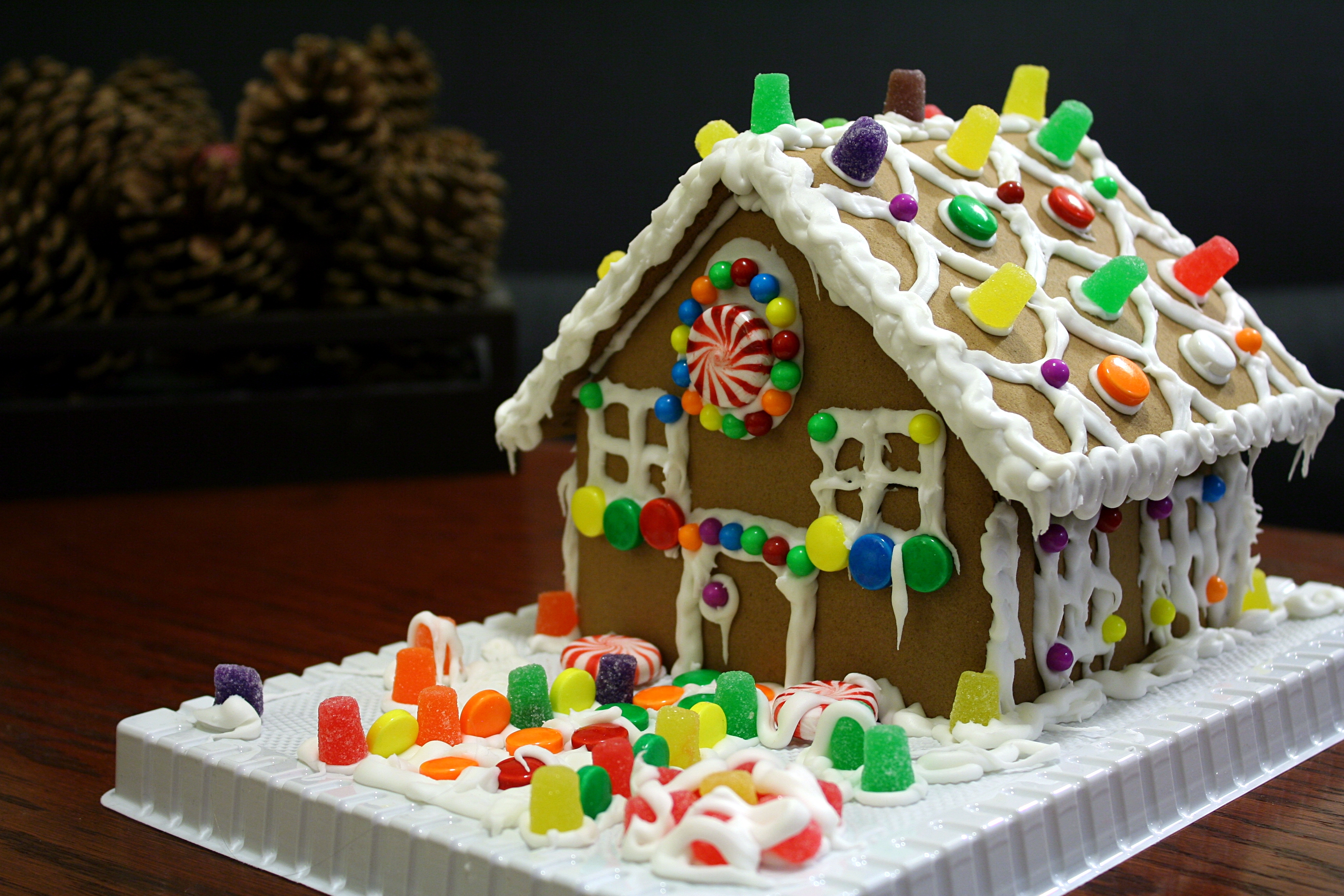 Completed gingerbread house on a white board, iced and decorated with gumdrops and candy