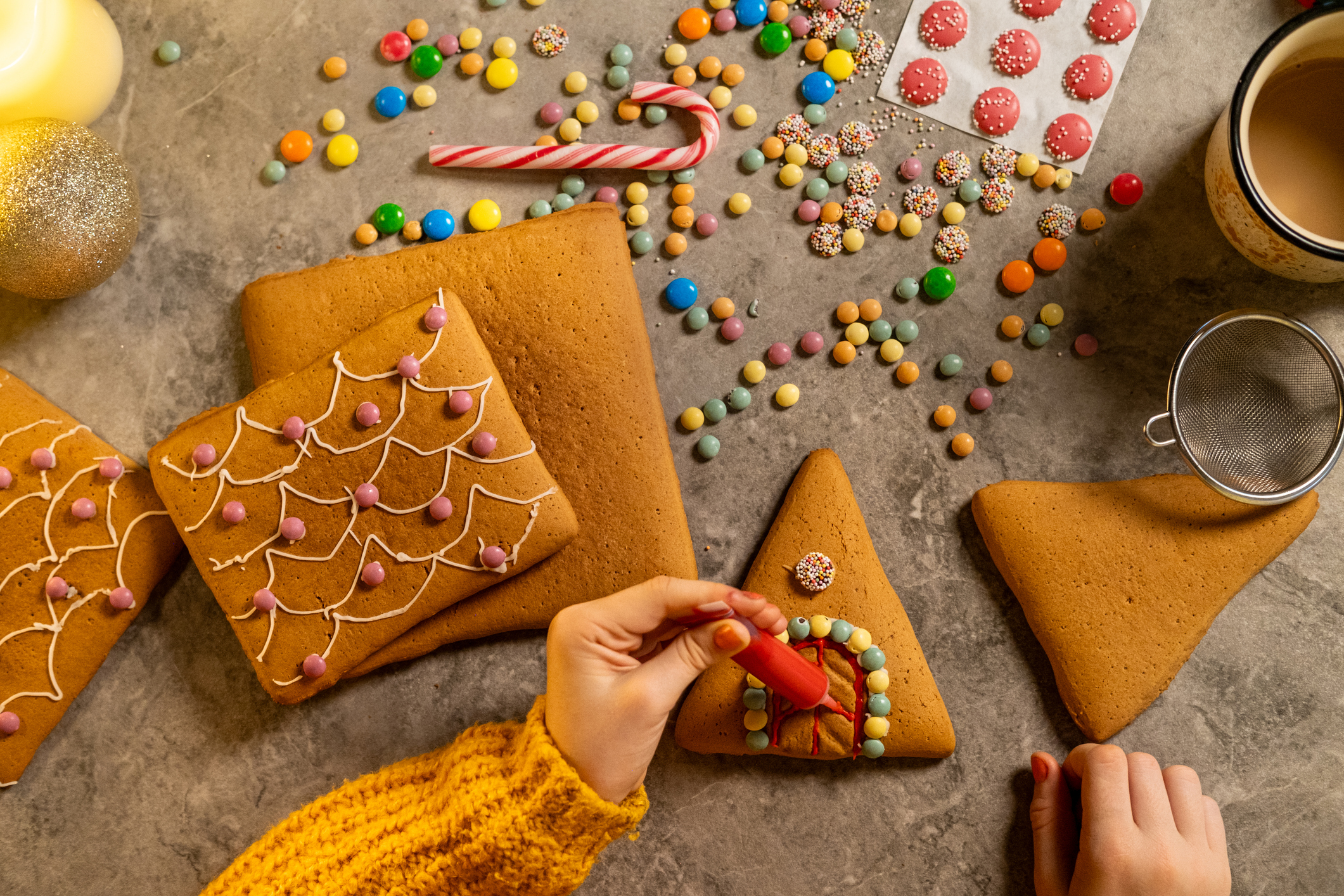 girl piping icing onto an already assembled gingerbread house