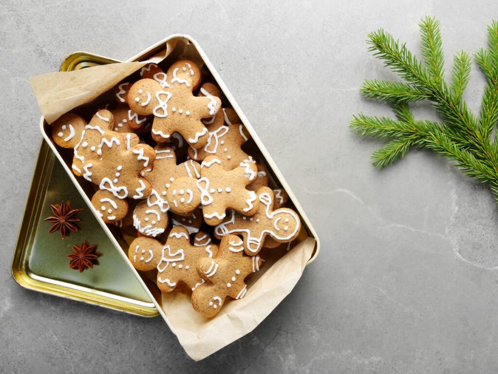 iced gingerbread men layered in a metal tin with parchment paper between them