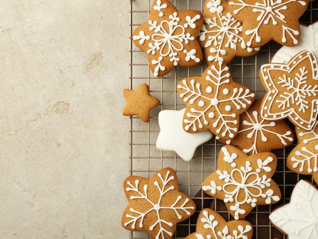 star shaped gingerbread cookies on a wire rack with white piped icing lines fully dried, one cookie flooded solid white