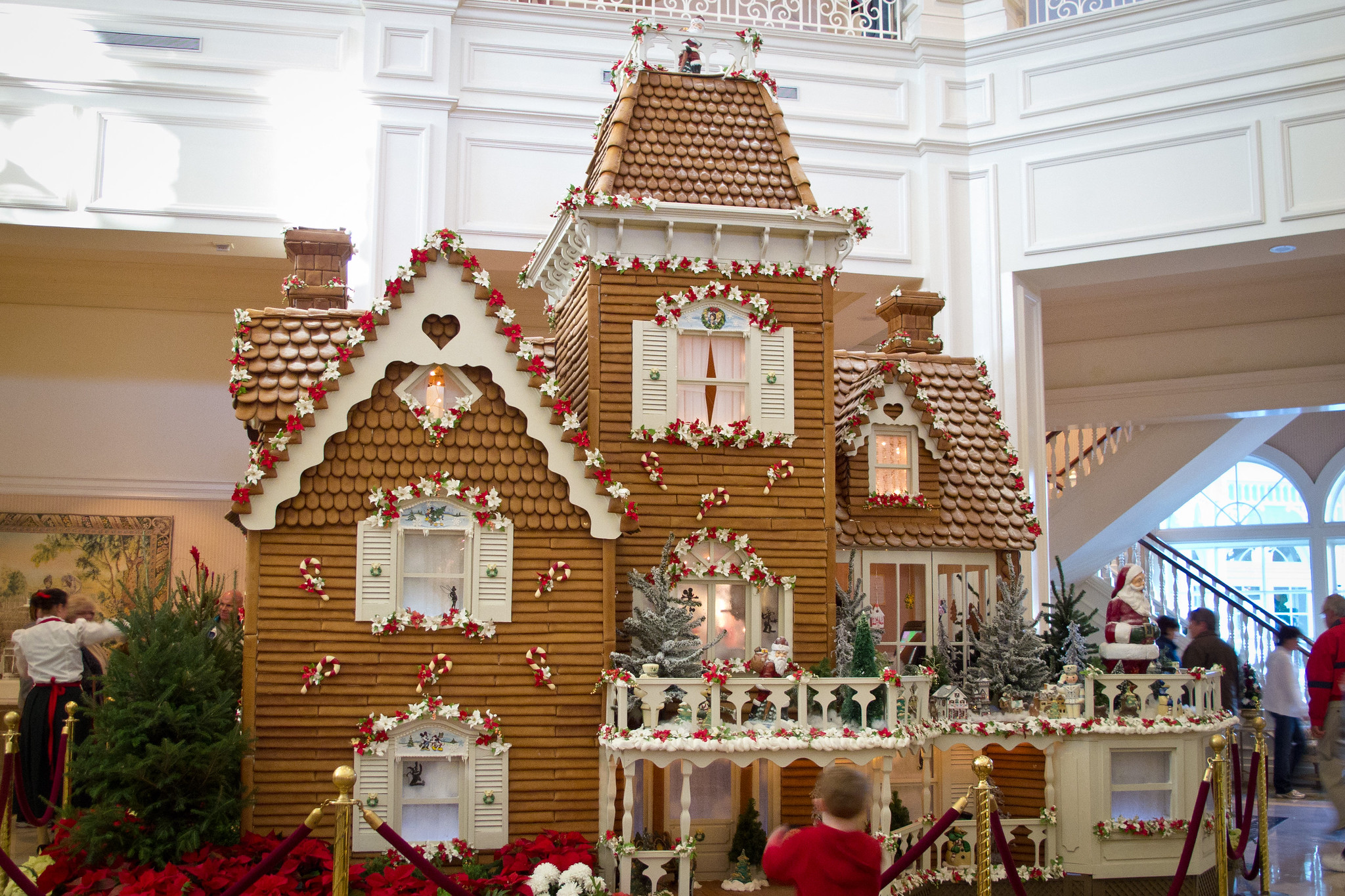 The life-size Grand Floridian gingerbread house in the resort lobby, with a shingled tower, white shutters and red and white garland