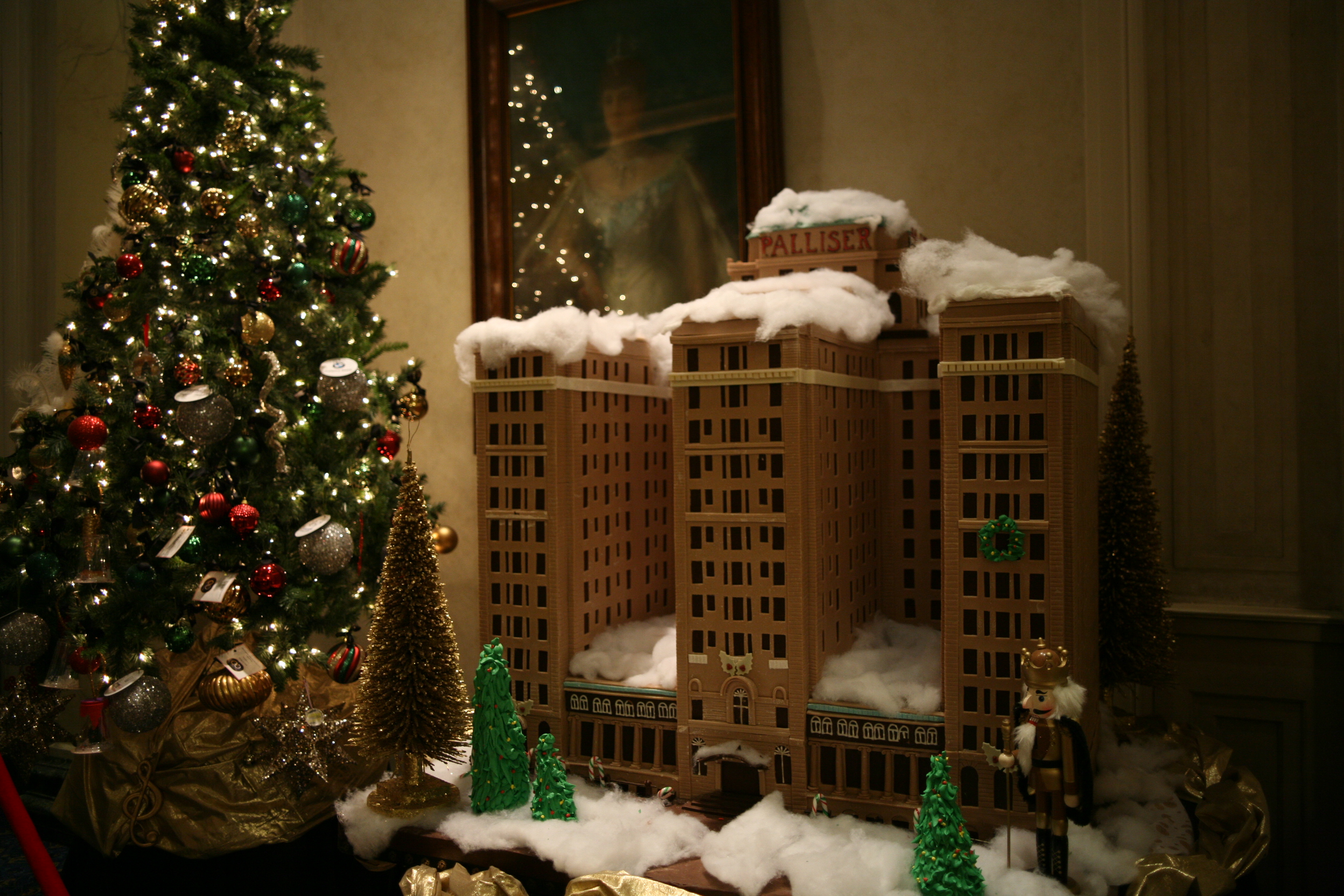 Tabletop gingerbread replica of the Palliser Hotel on cotton snow beside a lit Christmas tree and a nutcracker