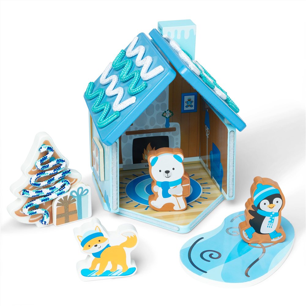 blue and white Melissa and Doug Winter Frost wooden gingerbread house with icing cords on the roof, a bear inside, and a fox, penguin and tree beside it